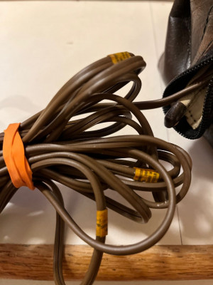 Three orange tags with writing stuck on the brown cord in three places.